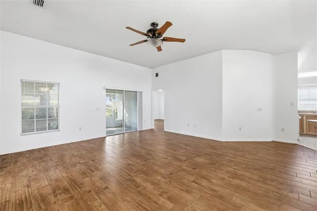 a view of empty room with wooden floor and ceiling fan
