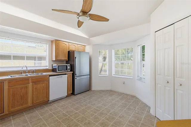 a kitchen with stainless steel appliances granite countertop a refrigerator a sink a stove with white cabinets