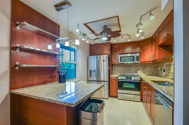 a kitchen with stainless steel appliances granite countertop a sink a stove and a wooden floors