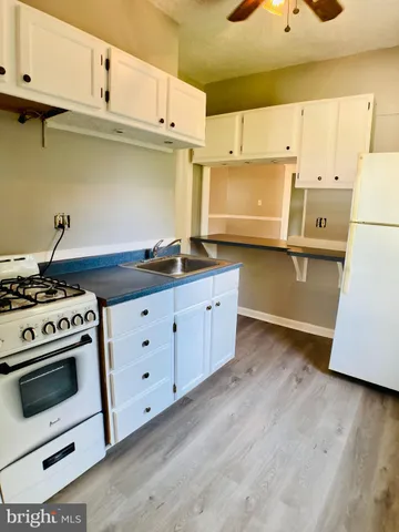 a kitchen with granite countertop a stove a sink and a refrigerator