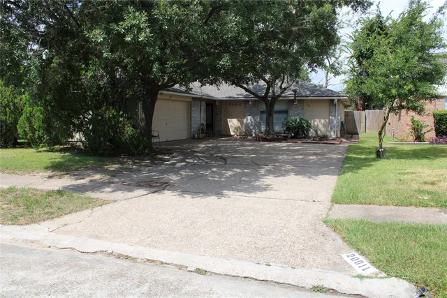 a view of a house with a yard and large tree