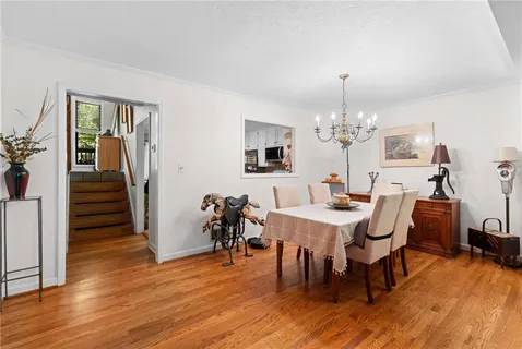 a living room with furniture dining table a large window and a chandelier