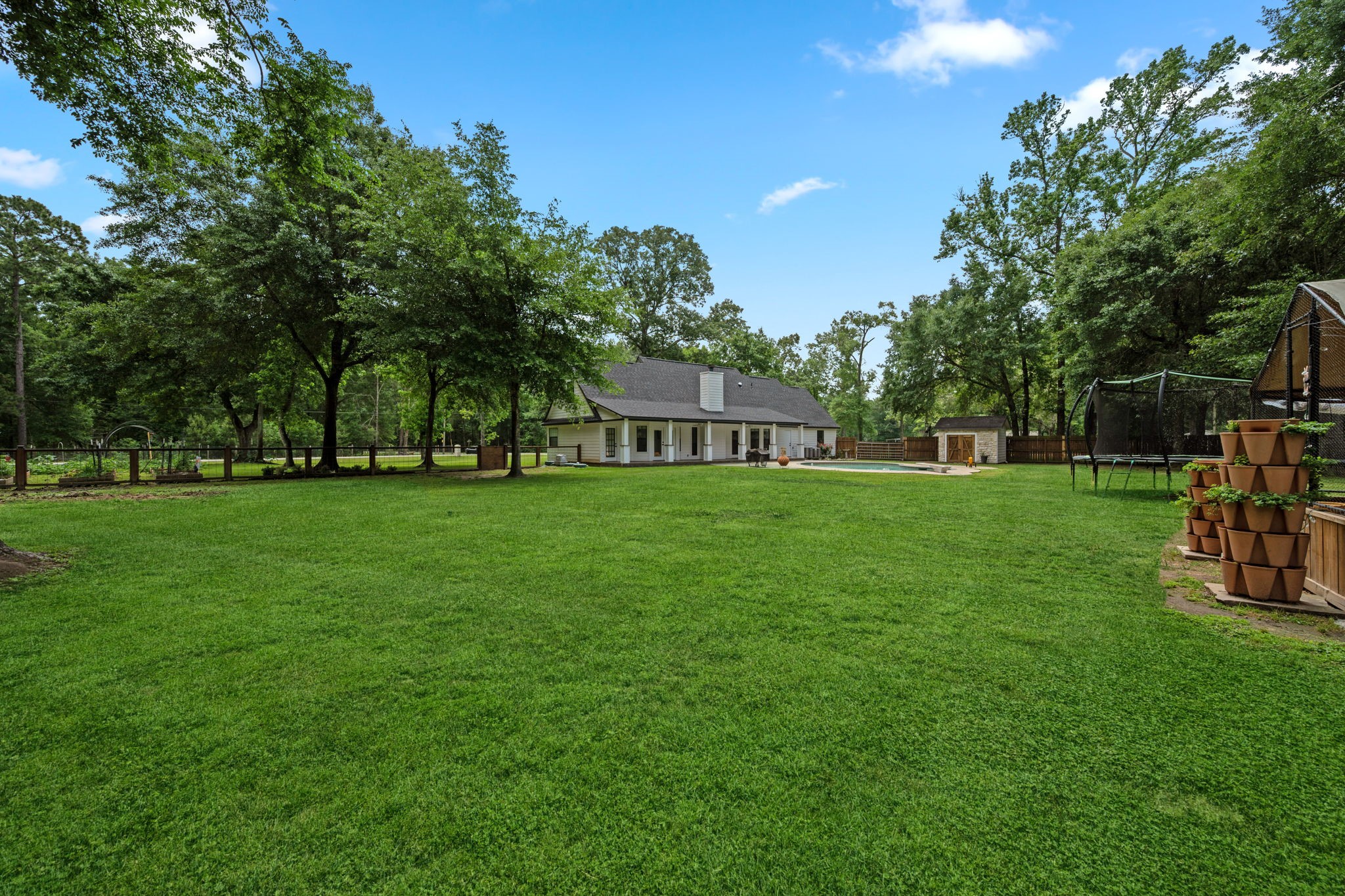 18 East Old Field Road Huffman, TX 77336 - Photo 33 of 35 Incredible backyard scale is on full display from this angle, showcasing the expansive fenced lawn, mature trees, & impressive depth of the homesite.