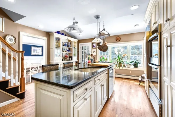 a kitchen with stainless steel appliances granite countertop a sink a stove and a wooden floors