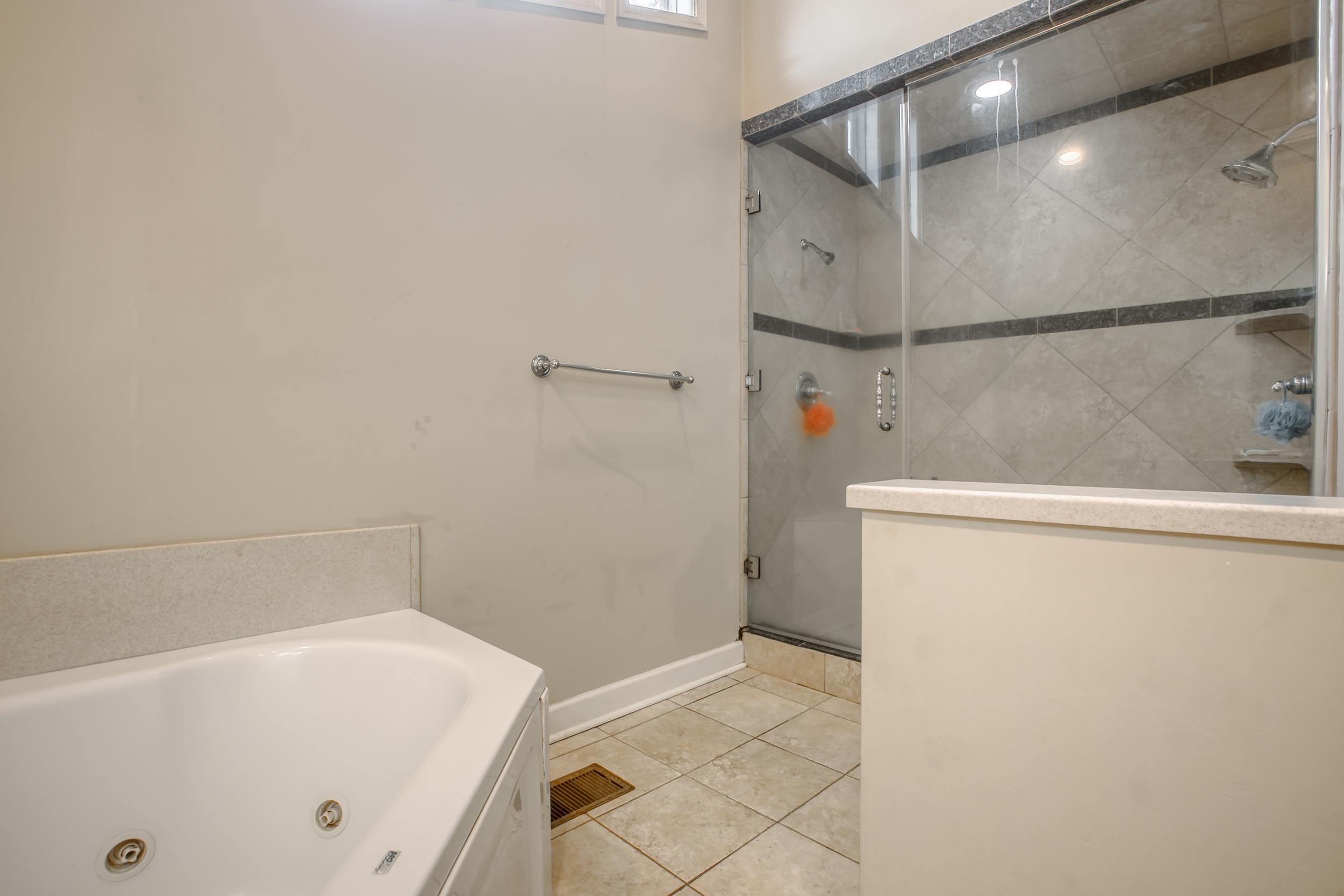 5680 North Angela Road Memphis, TN 38120 - Photo 24 of 33 Full bath with visible vents, a jetted tub, baseboards, a stall shower, and tile patterned floors