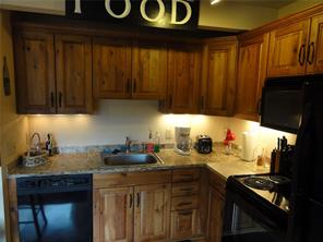 180 Evergreen Road, Unit 202E Dillon, CO 80435 - Photo 7 of 24 a kitchen with stainless steel appliances wooden cabinets and a stove top oven