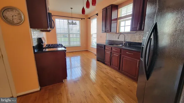 a kitchen with stainless steel appliances granite countertop a refrigerator a stove a sink and dishwasher with wooden floor