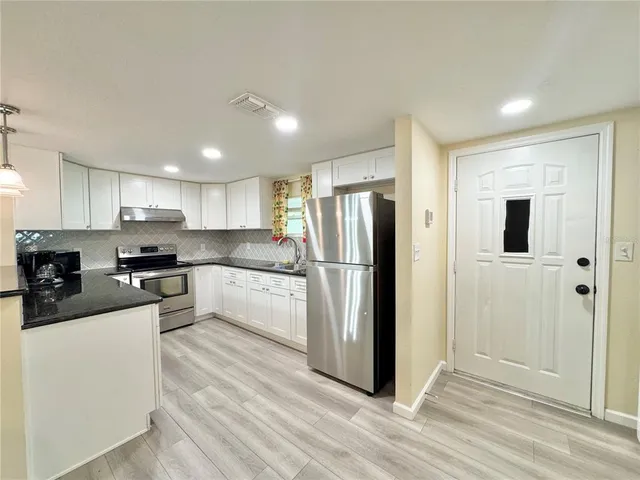 a kitchen with granite countertop a refrigerator and a sink