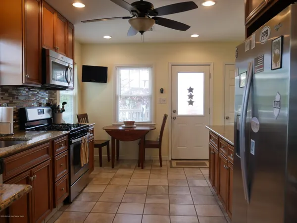 a kitchen with stainless steel appliances granite countertop a refrigerator a sink a stove top oven and a dining table