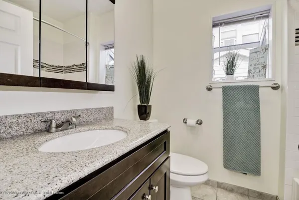 a bathroom with a granite countertop sink a toilet and a mirror