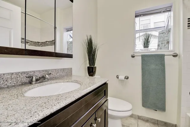 a bathroom with a granite countertop sink a toilet and a mirror