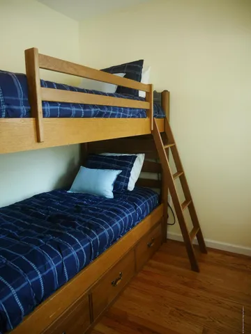 a bedroom with a bed chair and wooden floor