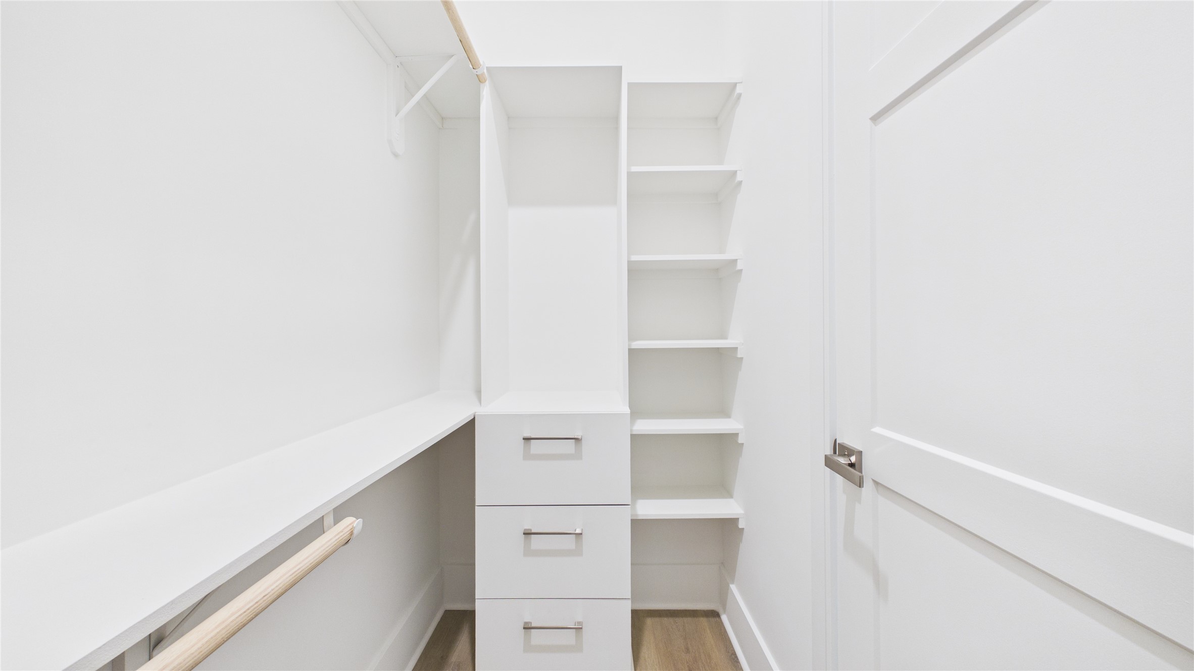 602 Skyland Terrace Way Houston, TX 77009 - Photo 24 of 40 This photo shows a bright, modern walk-in closet with ample shelving, hanging space, and three drawers, all in a sleek white finish.