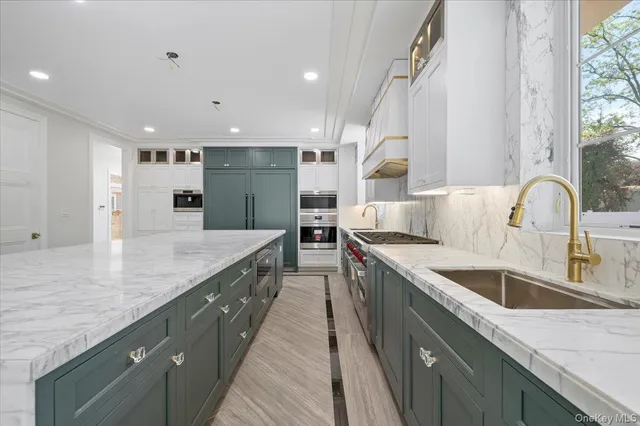 a large kitchen with stainless steel appliances granite countertop a sink and a large window
