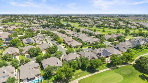 an aerial view of residential houses with outdoor space and trees