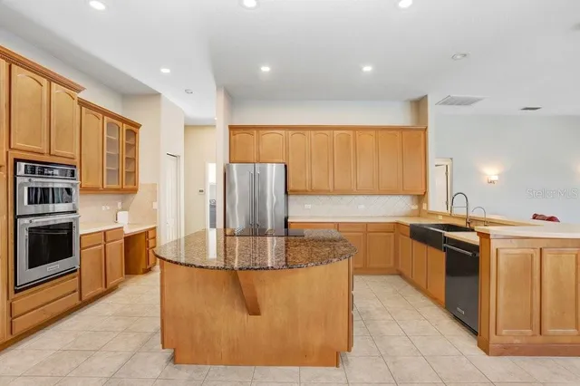 a kitchen with stainless steel appliances granite countertop a stove a sink and a refrigerator