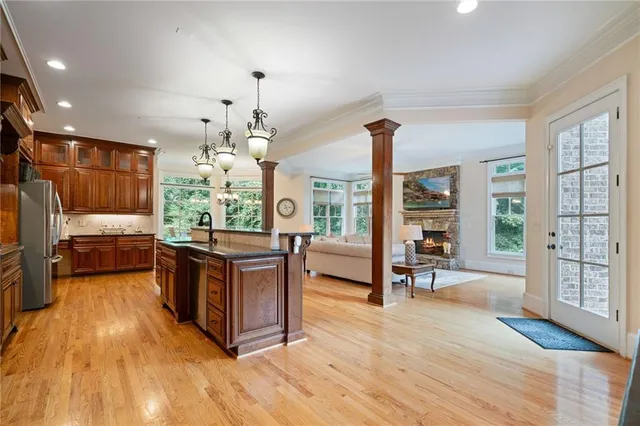 a kitchen with stainless steel appliances granite countertop a sink a stove and a wooden floor