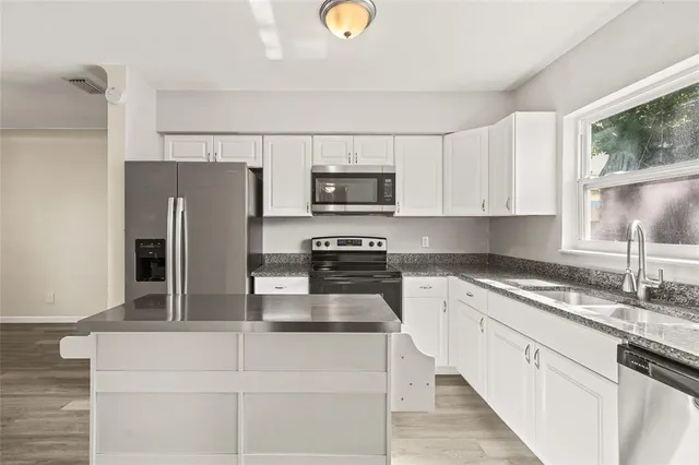 a kitchen with refrigerator a microwave a sink and cabinets