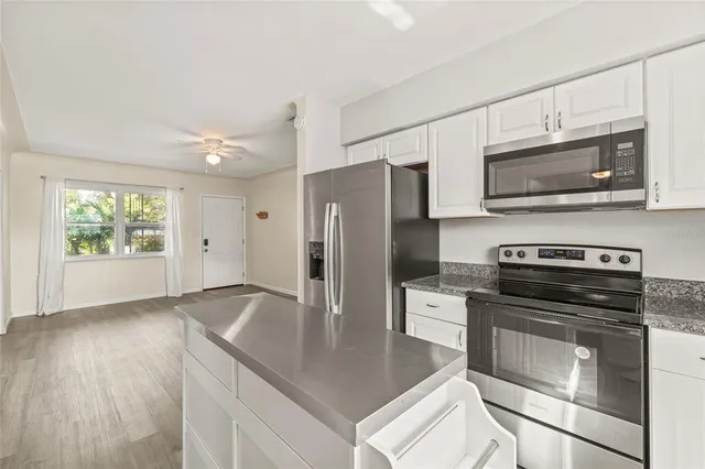 a kitchen with granite countertop a stove microwave and refrigerator