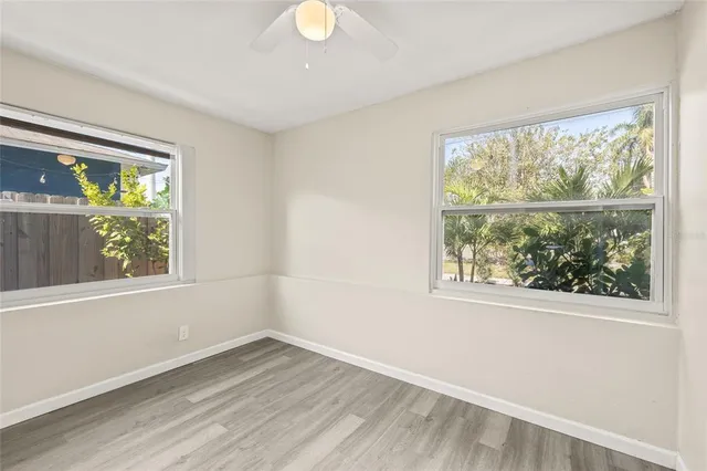 an empty room with wooden floor and fan