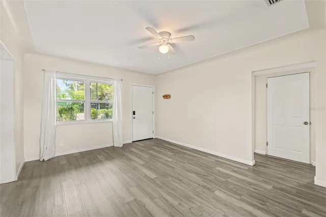 a view of an empty room with wooden floor and a window