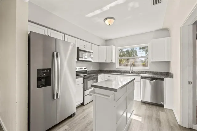 a kitchen with stainless steel appliances granite countertop a refrigerator a sink a stove a microwave and island