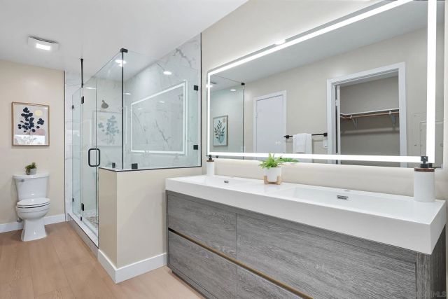 a spacious bathroom with a sink a toilet a large mirror and shower