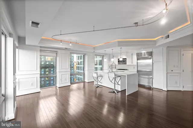 a room with stainless steel appliances wooden floors and large windows