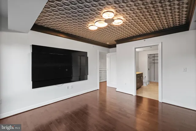 a view of a hallway with wooden floor kitchen and living room