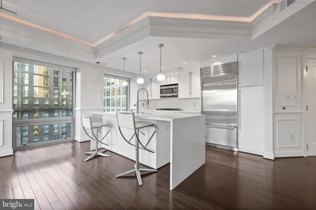 a kitchen with stainless steel appliances a refrigerator a sink dishwasher a stove and white cabinets with wooden floor