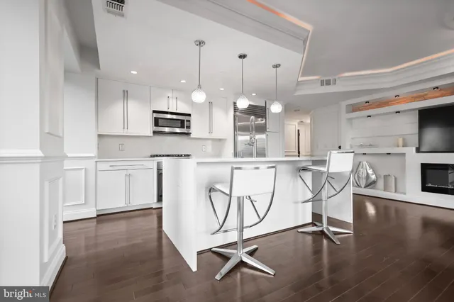 a kitchen with stainless steel appliances granite countertop a stove a sink a refrigerator and white cabinets with wooden floor