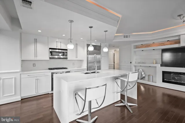 a kitchen with cabinets stainless steel appliances and wooden floor