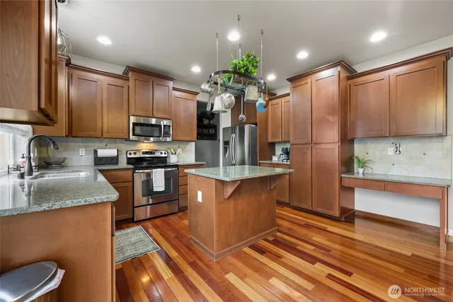 a kitchen with stainless steel appliances granite countertop a sink a stove and a wooden floors