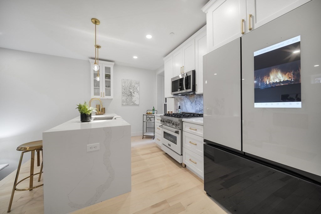 340 Meridian Street, Unit 1 Boston, MA 02128 - Photo 5 of 24 a kitchen with white cabinets and stainless steel appliances