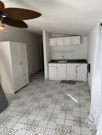 a kitchen with granite countertop a stove a window and white cabinets