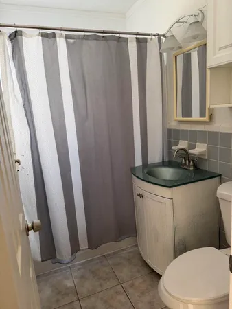 a bathroom with a sink a toilet a mirror and shower curtain