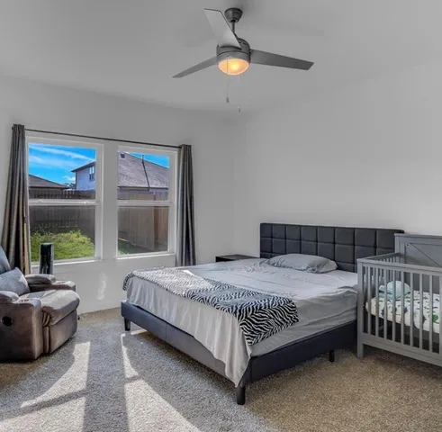 a bedroom with a bed couch and a large window
