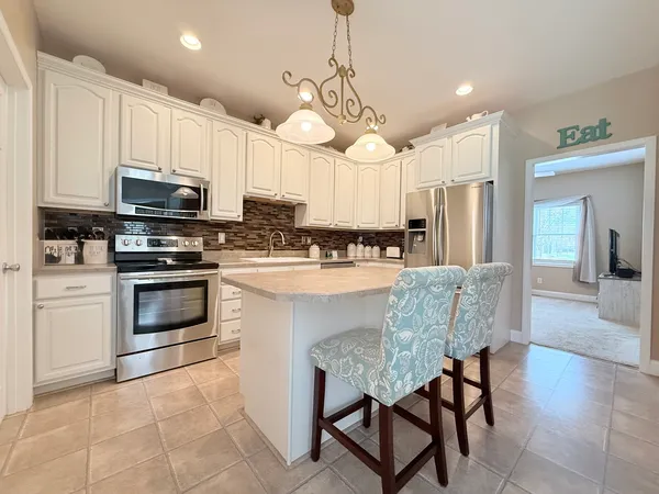 a kitchen with stainless steel appliances granite countertop a stove a sink a microwave a refrigerator and white cabinets