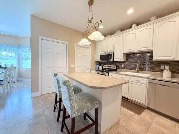 a kitchen with stainless steel appliances granite countertop a stove top oven a refrigerator a sink with a dining table and chairs