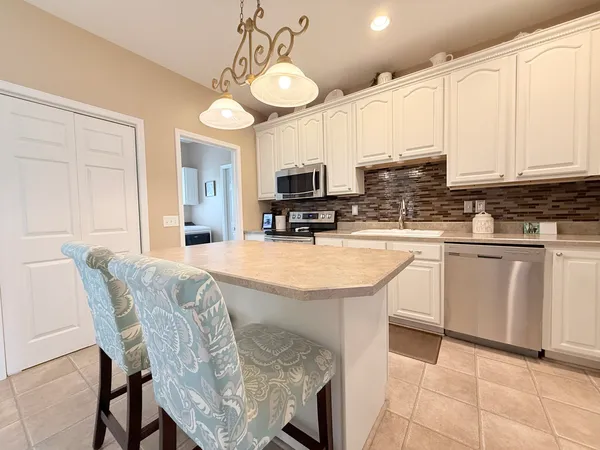 a kitchen with stainless steel appliances kitchen island granite countertop a sink a stove a dining table and chairs