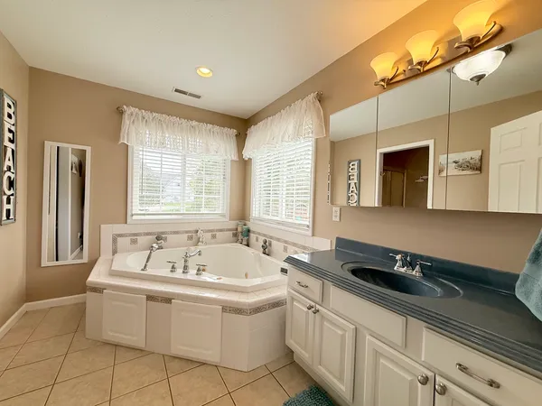 a spacious bathroom with a double vanity sink a mirror and a bathtub