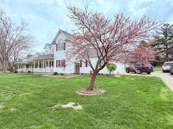 a front view of a house with a garden and trees