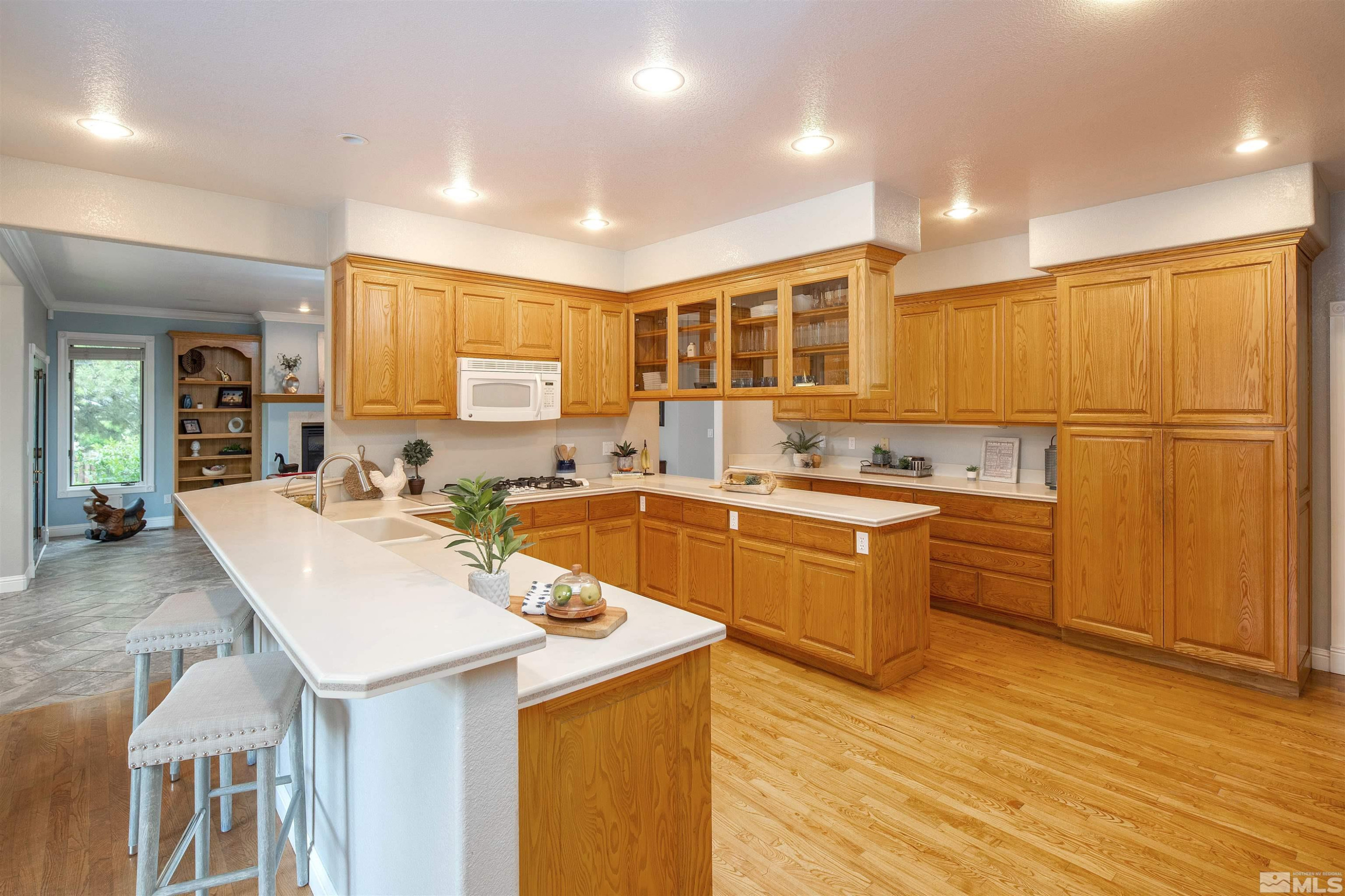 2032 Ash Canyon Road Carson City, NV 89703 - Photo 16 of 37 a large kitchen with kitchen island a sink a stove a refrigerator and a dining table with wooden floor
