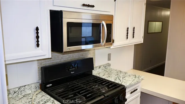a kitchen with granite countertop stainless steel appliances a stove and a microwave