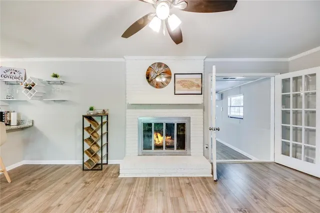 an empty room with wooden floor a chandelier fan and a fireplace