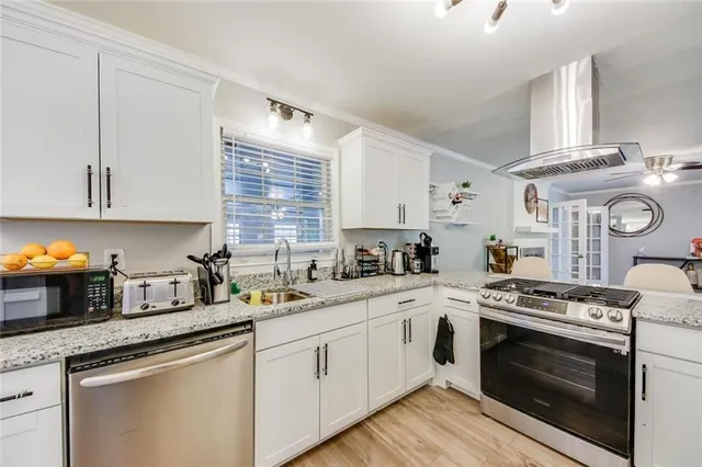 a kitchen with stainless steel appliances granite countertop a sink a stove and cabinets