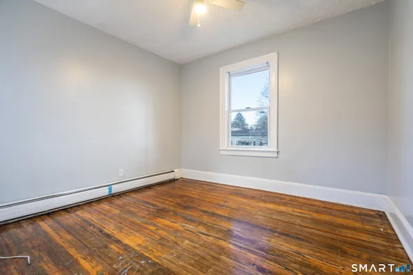 a view of an empty room with wooden floor and a window