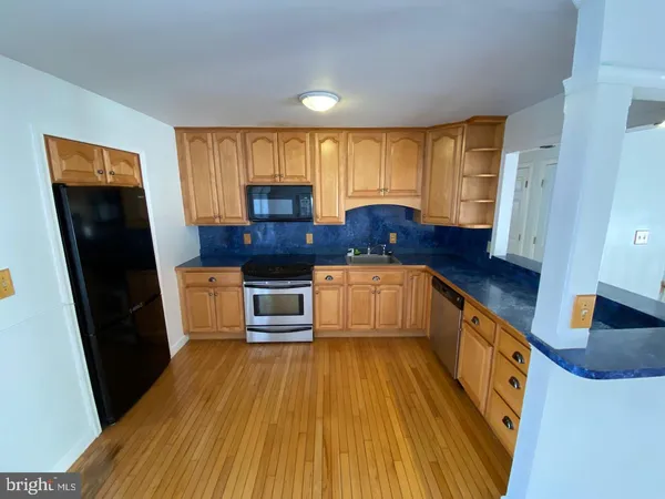 a kitchen with stainless steel appliances a stove a sink a refrigerator wooden floor and cabinets