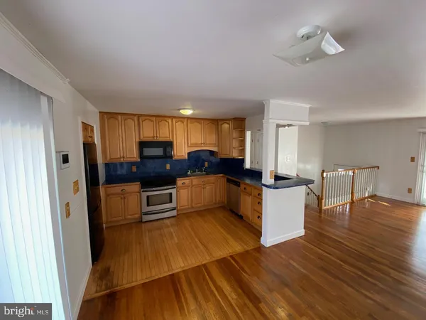 a large living room with stainless steel appliances kitchen island granite countertop a refrigerator and a stove top oven