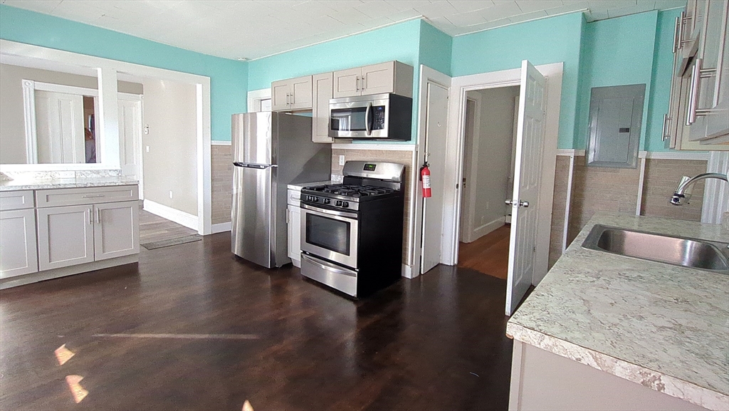 7 Cherry Street Lynn, MA 01902 - Photo 17 of 42 a kitchen with stainless steel appliances granite countertop a refrigerator a stove and a sink